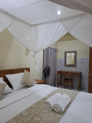 a bedroom with a bed with two towels on it at Kelle Homestay in Sidemen
