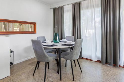 a dining room table with chairs and a vase on it at Garden Hideaway in Tewantin