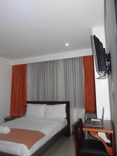 a bedroom with a bed and a desk and a television at Hotel Lancers Casimena Yopal in Yopal