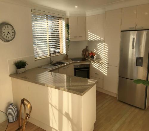 a kitchen with white cabinets and a stainless steel refrigerator at Headlands at Black Head in Hallidays Point