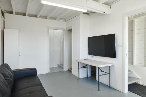 a white living room with a tv and a desk at The Boat House in Hallidays Point
