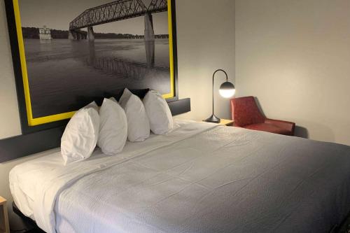 a bedroom with a large white bed with a red chair at Super 8 by Wyndham Kirksville-University Area in Kirksville