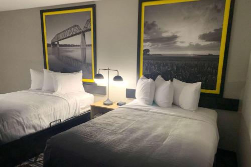 a hotel room with two beds and a picture on the wall at Super 8 by Wyndham Kirksville-University Area in Kirksville