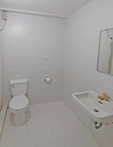 a white bathroom with a toilet and a sink at Doña Mercedes in Cebu City