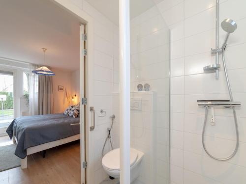 a bathroom with a shower and a toilet and a bed at Holiday Home in Quiet Dutch Park for Families in Wemeldinge