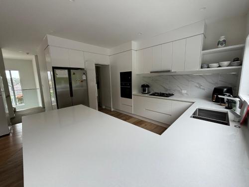 a kitchen with white cabinets and a white counter top at Dream House 2 in Auckland