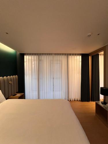 a bedroom with a large white bed and curtains at Haeundae La Mer in Busan