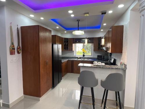 a kitchen with a purple ceiling and two bar stools at Hermoso Apartamento con Jacuzzi Privado in Punta Cana