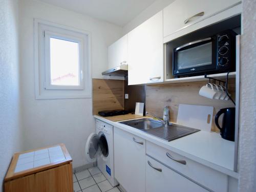 une petite cuisine avec un évier et un micro-ondes dans l'établissement Appartement cosy 2 pièces près du lac et des thermes - FR-1-498-110, à Neuvecelle