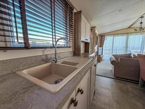 een keuken met een spoelbak en een woonkamer bij Beautiful Caravan With Stunning Sea Views At Haven Hopton Ref 80001H in Great Yarmouth