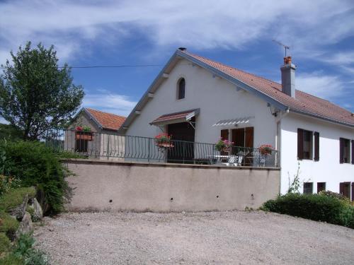 a white house with a balcony with flowers on it at Gîte Les Hirondelles in Plombières-les-Bains