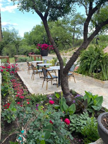 a garden with a table and chairs and flowers at Blair House Inn and Spa in Wimberley