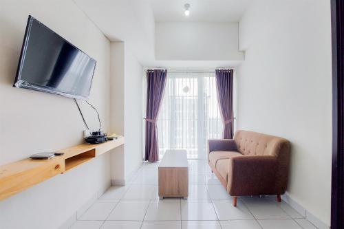 a living room with a couch and a television at Nice and Comfy 1BR at Casa De Parco Apartment By Travelio in Tangerang
