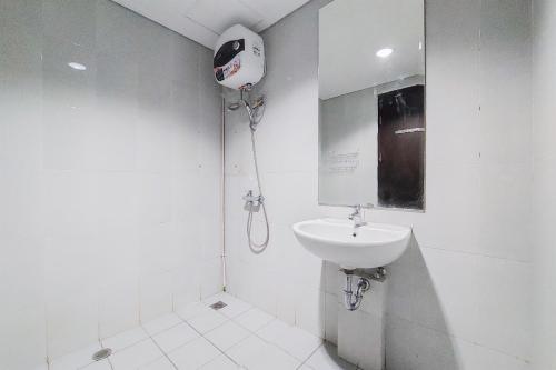 a white bathroom with a sink and a hair dryer at Nice and Comfy 1BR at Casa De Parco Apartment By Travelio in Tangerang