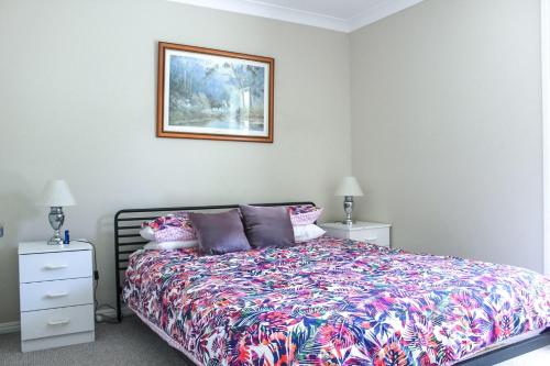 a bedroom with a bed and a picture on the wall at Central Hideaway at Black Head in Hallidays Point