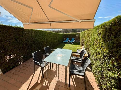 eine Terrasse mit einem Tisch und Stühlen unter einem Sonnenschirm in der Unterkunft Ferienhaus Casa Fluvià mit Gemeinschaftspool in L'Estartit in Torroella de Montgrí