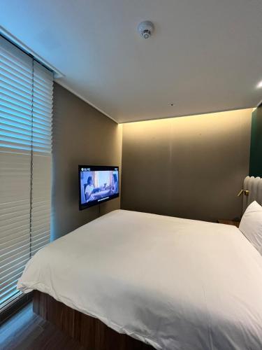 a bedroom with a large bed with a tv on the wall at Haeundae La Mer in Busan