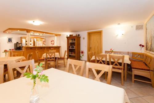 a dining room with white tables and wooden chairs at Wellness Ferienwohnungen Zellertalblick in Drachselsried