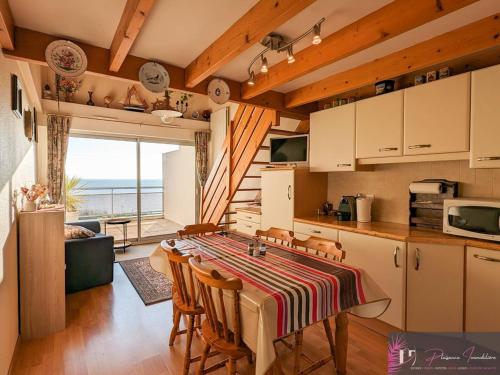 une cuisine avec une table et des chaises dans une pièce dans l'établissement Duplex avec piscine et vue sur l'océan à La Rochelle - FR-1-825-14, à La Rochelle
