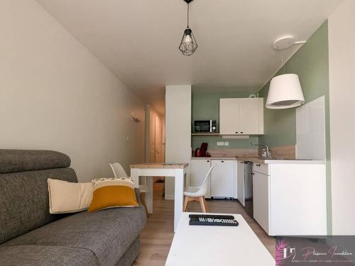 un salon avec un canapé et une table et une cuisine dans l'établissement Studio rénové avec jardin et accès piscine - FR-1-825-19, à La Rochelle