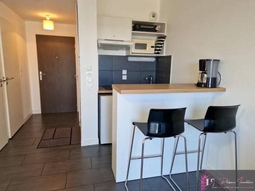 une cuisine avec deux tabourets de bar noirs à un comptoir dans l'établissement Studio meublé avec Wifi à La Rochelle - FR-1-825-37, à La Rochelle