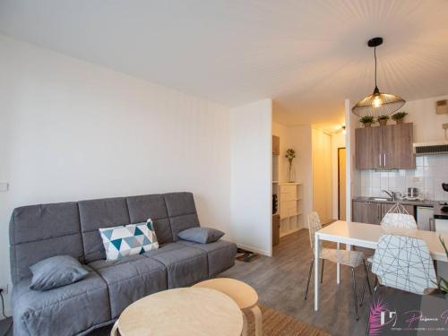 un salon avec un canapé gris et une table dans l'établissement Studio rénové à 50m de l'océan à La Rochelle - FR-1-825-41, à La Rochelle