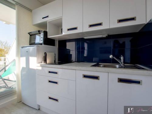 une cuisine blanche avec un évier et un micro-ondes dans l'établissement Studio bis avec balcon à La Rochelle, parking inclus - FR-1-825-16, à La Rochelle