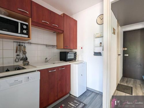 une cuisine avec des armoires en bois et un réfrigérateur blanc dans l'établissement Appartement T2 meublé avec parking à 200m de la plage - FR-1-825-18, à La Rochelle