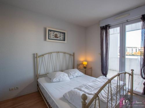 une chambre avec un lit avec des draps blancs et une fenêtre dans l'établissement Grand duplex avec terrasse et piscine - FR-1-825-62, à La Rochelle