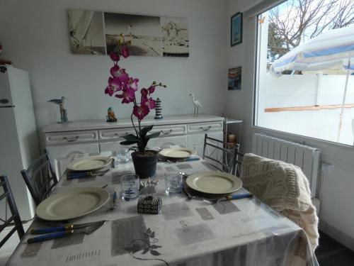 - une table à manger avec des assiettes et des ustensiles dans l'établissement Maison de vacances à Fromentine proche plage, quartier prisé, terrasse, parking - FR-1-540-319, à La Barre-de-Monts