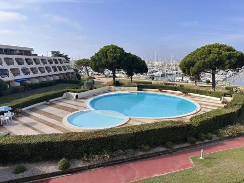 une grande piscine devant un immeuble dans l'établissement Studio moderne avec climatisation et parking proche plage - FR-1-731-132, au Grau-du-Roi