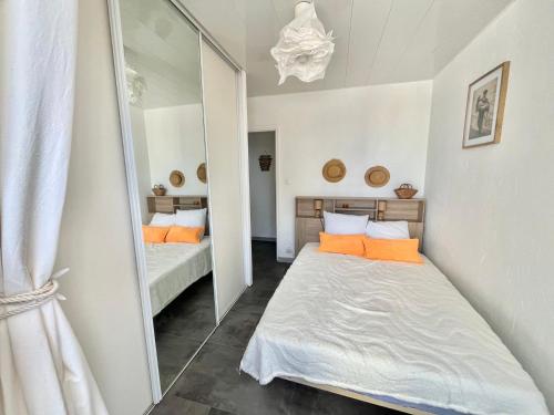 une petite chambre avec un lit et un miroir dans l'établissement Appartement lumineux sur plage avec piscine et parking - FR-1-716-81, au Grau-du-Roi