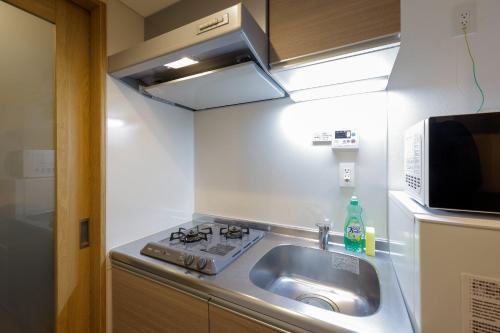 a small kitchen with a sink and a microwave at Cortile YotsuyaHonshiocho in Tokyo