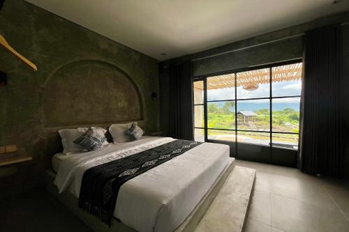 a bedroom with a large bed with a large window at Batur Sunsun Kintamani in Kubupenlokan
