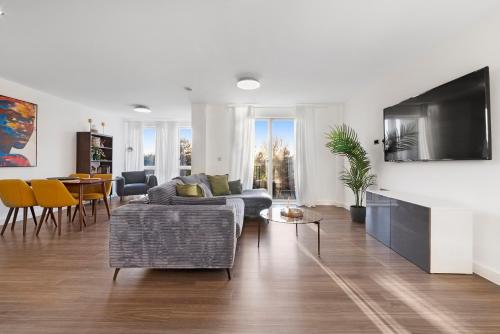 a living room with a couch and a tv at Heart Of Stratford Olympic Park 3 Bedroom in London