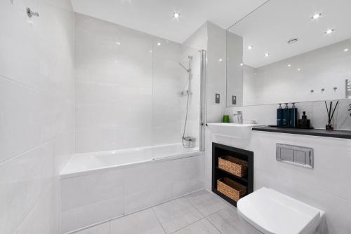 a white bathroom with a tub and a toilet and a sink at Heart Of Stratford Olympic Park 3 Bedroom in London