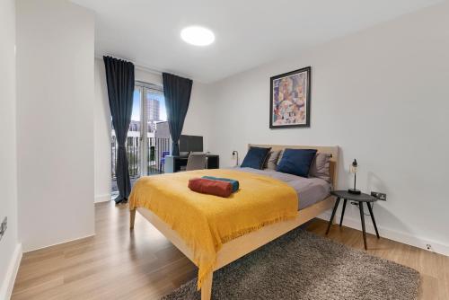 a bedroom with a bed with a yellow blanket at Heart Of Stratford Olympic Park 3 Bedroom in London