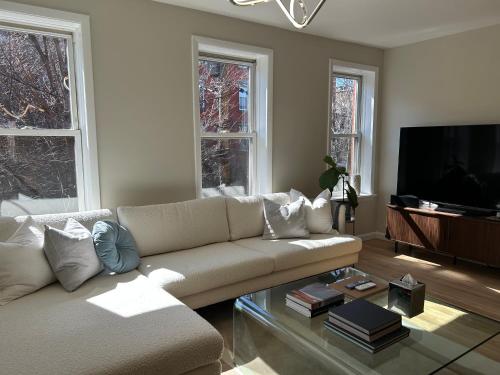 a living room with a couch and a flat screen tv at NEW! Historic Townhouse-14 min to WTC in Jersey City