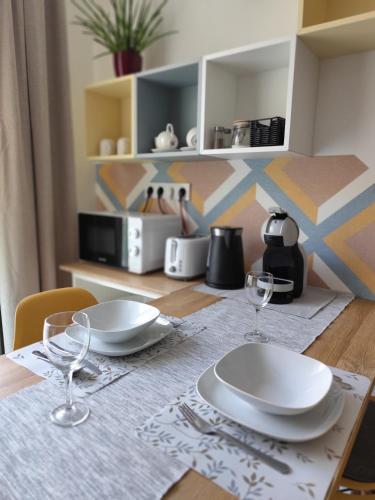 a table with two plates and wine glasses on it at Három Hegy Apartman Lillafüred in Lillafüred