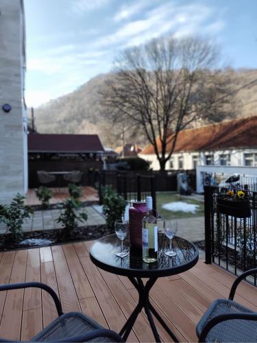 a table with wine glasses on a wooden deck at Három Hegy Apartman Lillafüred in Lillafüred