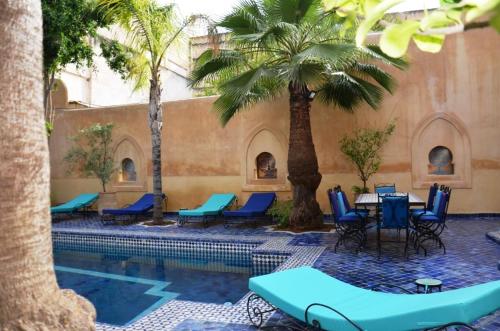 a pool with chairs and a table and palm trees at Chambres Émeraude et Rubis - Riad Lotus Bleu in Fès
