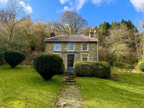 an old stone house with a blue door in a field at Pass the Keys Y Bwythn Welsh Countryside Retreat UK Getaway in Carmarthen