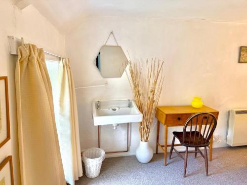 a bathroom with a sink and a table with a chair at Pass the Keys Y Bwythn Welsh Countryside Retreat UK Getaway in Carmarthen