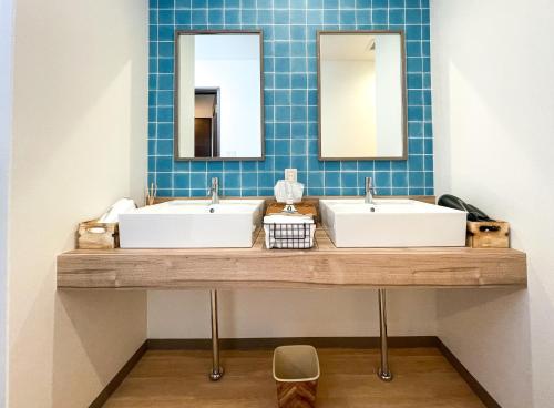 a bathroom with two sinks and two mirrors at Guesthouse NALUノ道 in Kobe