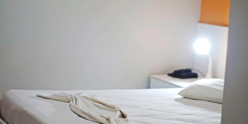 a white bed in a bedroom with a light on at Hotel Americas in Fortaleza
