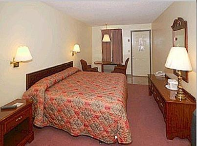 a hotel room with a bed and two tables and chairs at Mountain Empire Motel in Mountain City