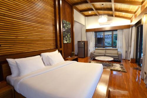 a bedroom with a large bed and a living room at The Hidden Village, Khao Yai in Mu Si