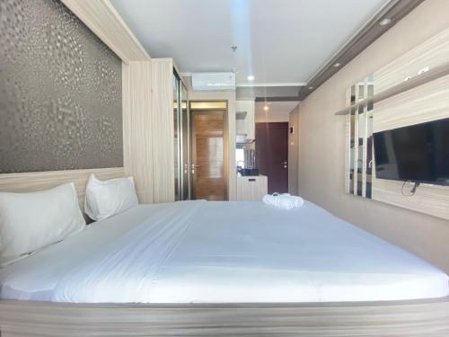a bedroom with a large white bed and a television at Modern and Cozy Studio Room at Gateway Pasteur Apartment By Travelio in Bandung
