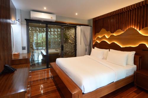 a bedroom with a large bed with a wooden headboard at The Hidden Village, Khao Yai in Mu Si