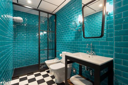 baño de azulejos azules con lavabo y aseo en Room Mate Valeria en Málaga